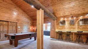 Ein Holzinterieur mit Billardtisch, einer Bar mit Hockern und einem Schild an der Wand.