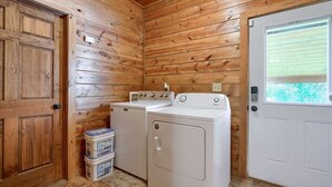 Ein Waschraum mit Holzwänden, einer weißen Tür und zwei weißen Waschmaschinen.