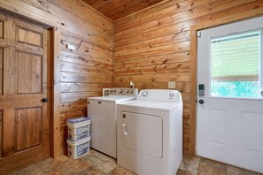 Un lavadero con paredes de madera, una puerta blanca y dos lavadoras blancas.