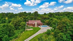 A house with a red roof, surrounded by lush greenery and a clear blue sky.