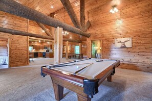 A pool table in a wooden room with a high ceiling and exposed beams.