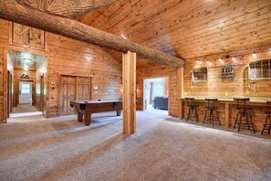 Ein Holzinterieur mit Billardtisch, Bar und einer hohen Holzbalkendecke.