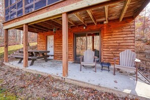 A log cabin with a covered porch, a picnic table, and two Adirondack chairs. - Water's Edge | Hocking Hills, Pond, Hot Tub, Pets (Logan)