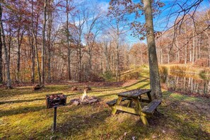 A forested campsite with a picnic table and a fire pit.