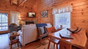 A cozy cabin interior with a fireplace, a dining table, and a sofa.
