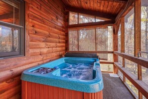 A wooden cabin with a hot tub and a deck.