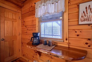 A wooden cabin interior with a window, a coffee maker, and two mugs on a counter. - Water's Edge | Hocking Hills, Pond, Hot Tub, Pets (Logan)