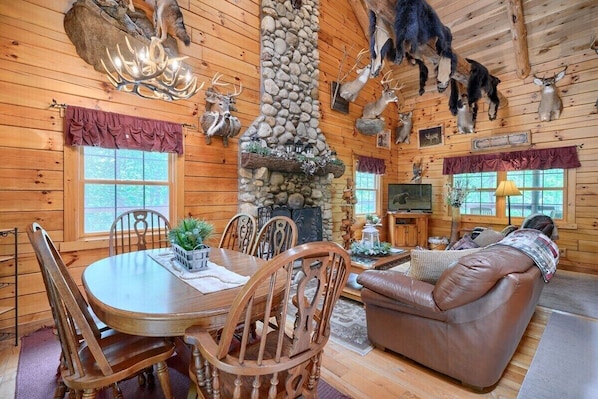 L’intérieur d’une cabane en rondins, avec une cheminée en pierre, une table à manger en bois et un canapé en cuir.