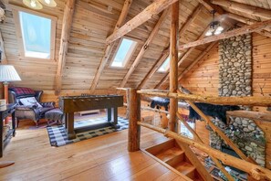 Ein gemütliches Blockhaus-Interieur mit einem Kicker, einem Kamin und einer Steinwand.