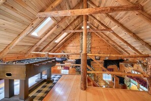 A rustic wooden interior with a high ceiling, wooden beams, and a foosball table.