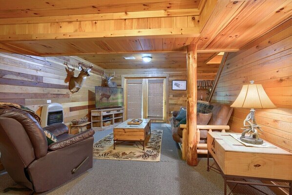 A cozy log cabin interior with a leather recliner, a wooden coffee table, and a lamp.