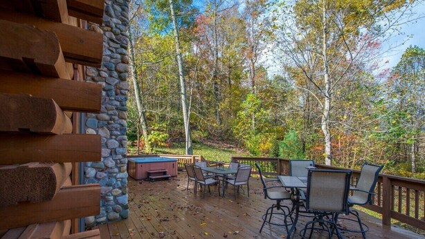 A wooden deck with outdoor furniture and a stone wall.