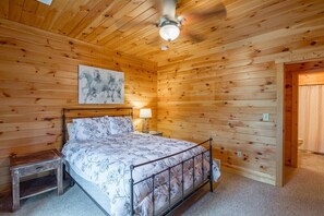 A wooden-paneled bedroom with a bed, bedside table, and a ceiling fan.