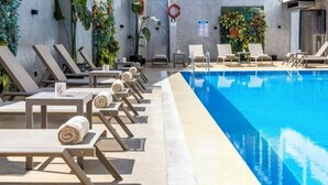 A poolside area with sun loungers, a clear blue pool, and decorative plants. - Ramada Plaza by Wyndham Istanbul Sultanahmet (Istanbul)