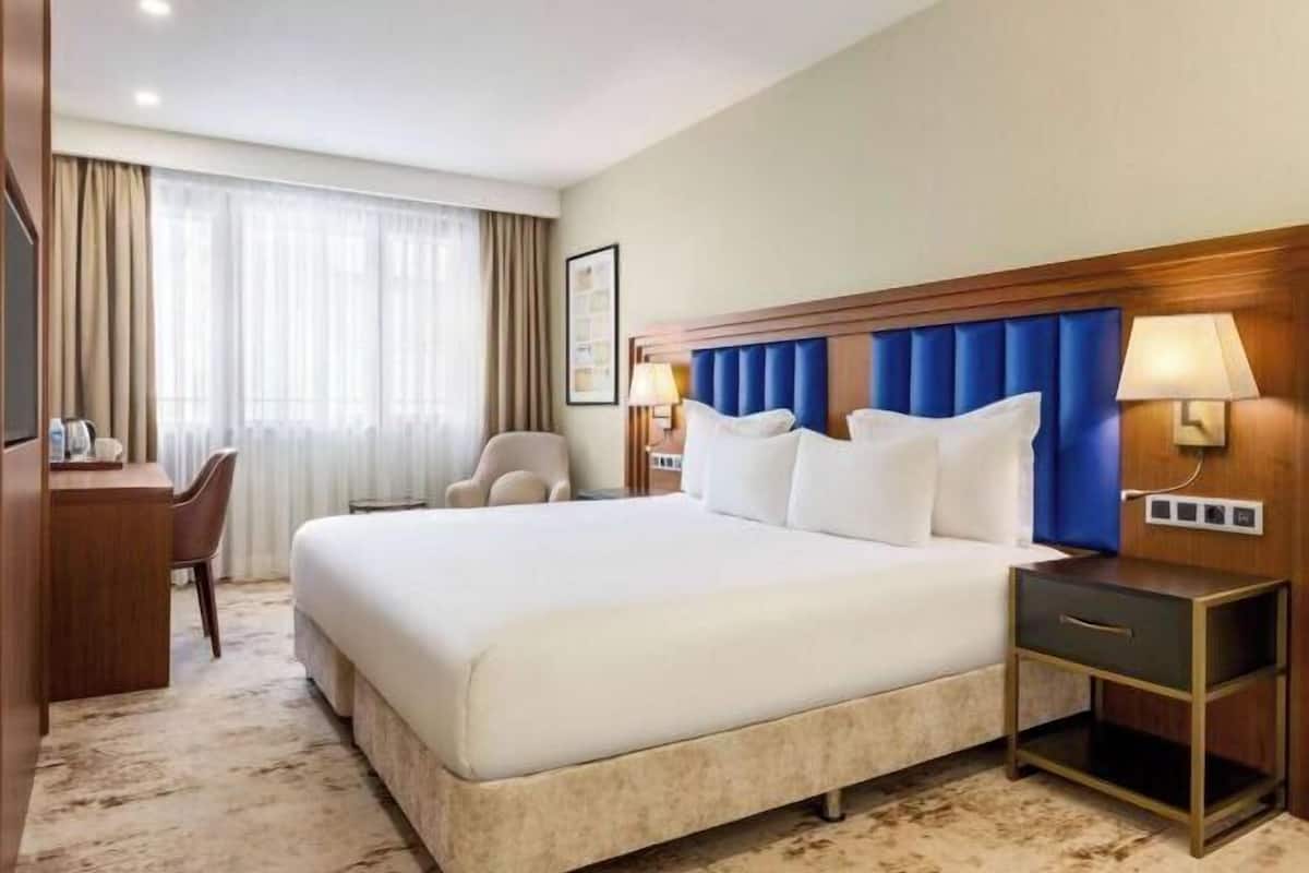 Une chambre d’hôtel avec un grand lit, un bureau, une chaise et une table de chevet.