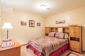 A bedroom with a bed, a wooden nightstand, a lamp, and a wooden cabinet.