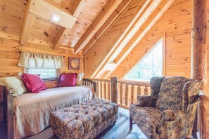 A cozy cabin room with a bed, a cushioned bench, and a chair.