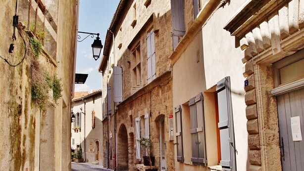 A narrow cobblestone street lined with historic buildings featuring arched doorways and traditional shutters. - Gîte La Parenthèse In a quiet Languedoc village, 8 minutes from Pézenas (Caux)