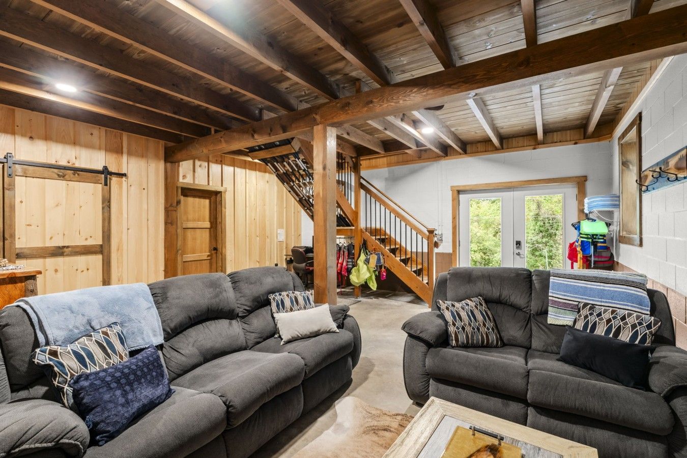 A spacious living area with two sofas, a coffee table, and a staircase leading to an upper level.