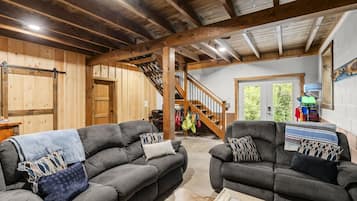 A spacious living area with two sofas, a coffee table, and a staircase leading to an upper level.