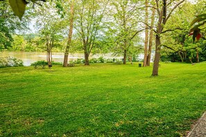 Un parque con césped, árboles y un lago al fondo.