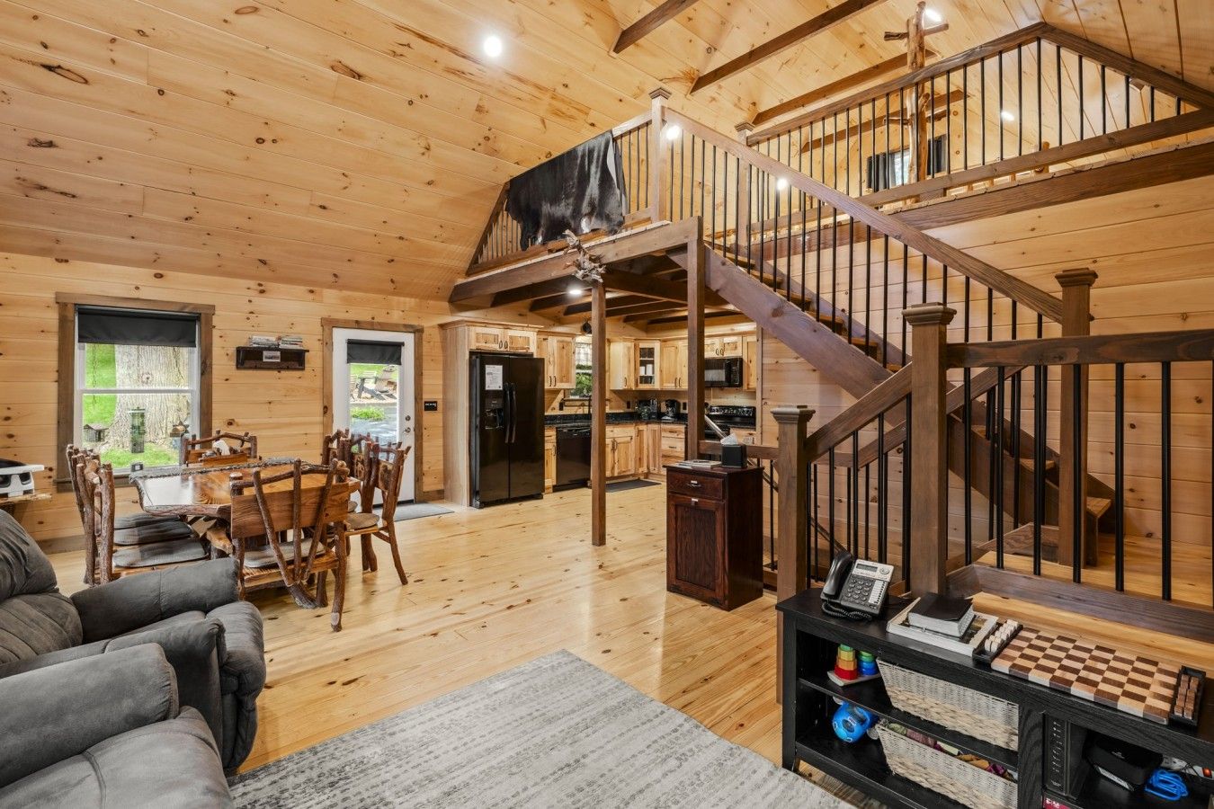 A spacious living area with a wooden staircase, a dining table, and a cozy seating area.