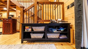 A wooden staircase with a black railing, a wooden cabinet with baskets, and a laptop on top.