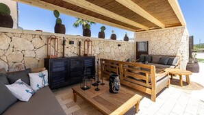 An outdoor patio with stone walls, wooden furniture, and potted cacti. - Cala Coralli (Syracuse)