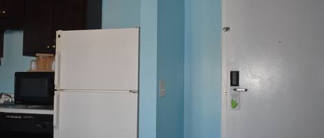 A kitchen with a white refrigerator, a microwave, and dark cabinets.