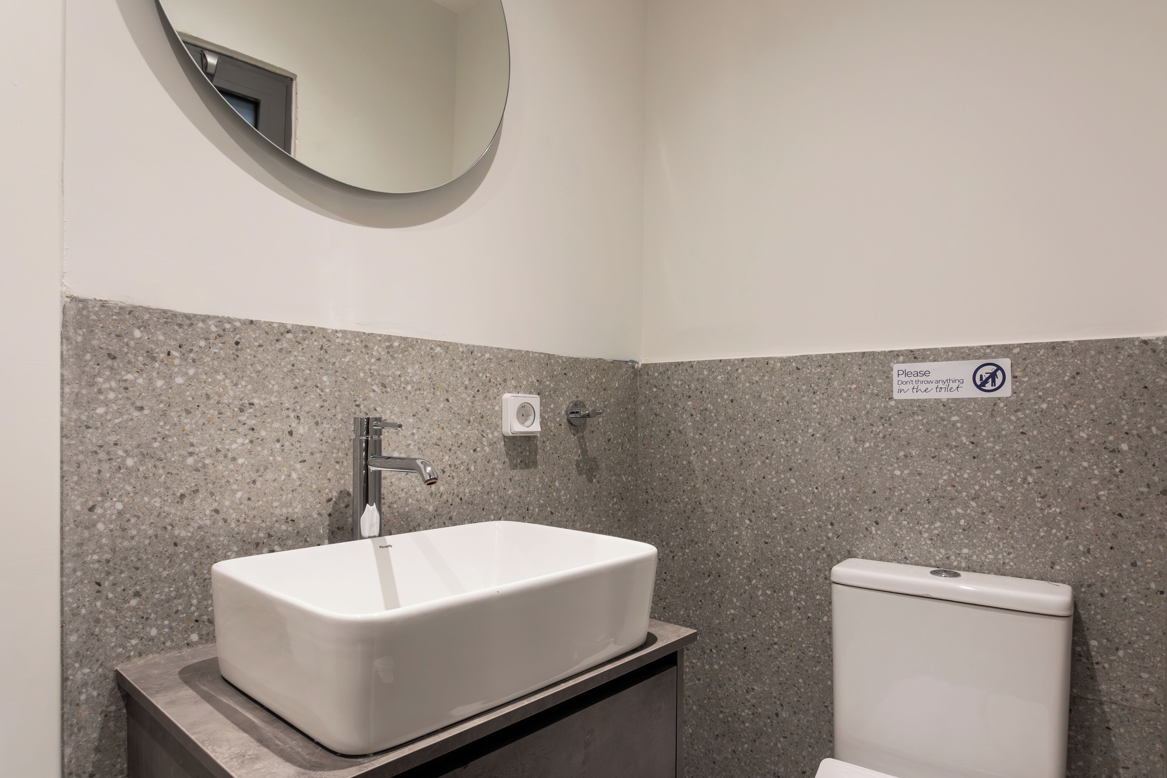 Un baño con un lavamanos blanco, un espejo y un inodoro.