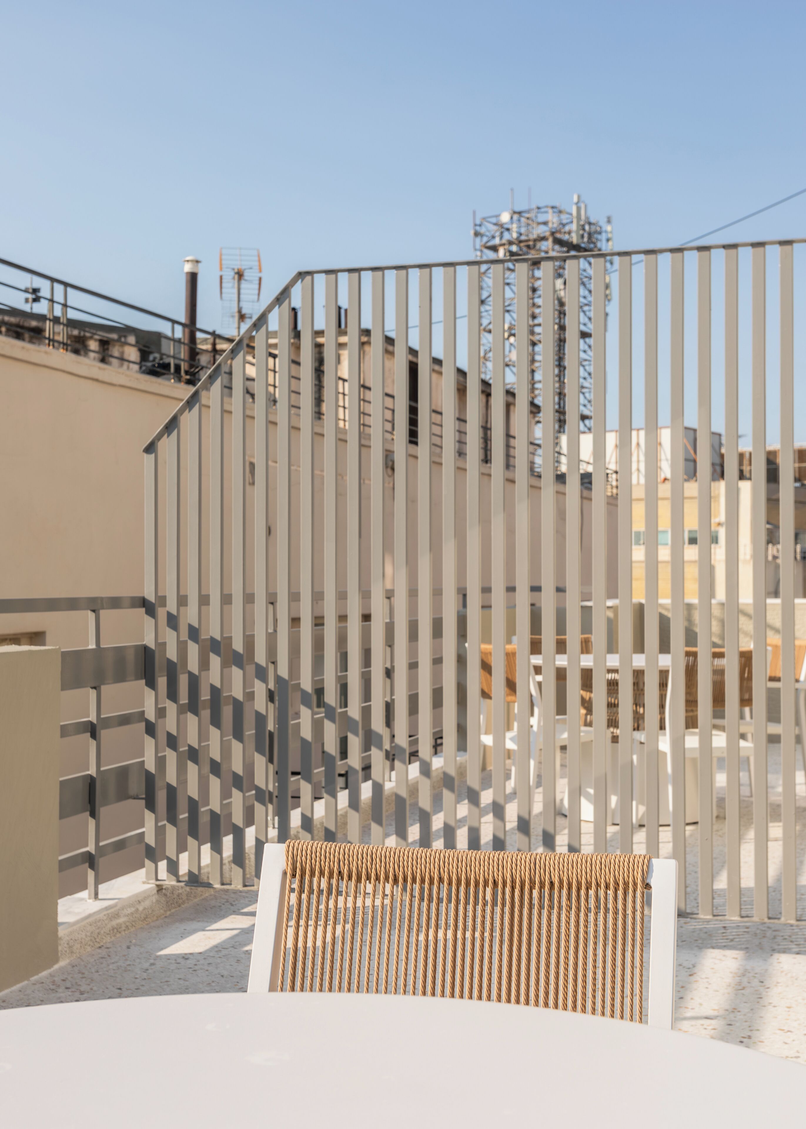 A modern outdoor seating area with a metal fence and a view of industrial buildings in the background.