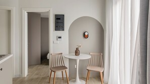 A modern kitchen with white cabinets, a round dining table, and two wooden chairs. - SOL by Zoia Living (Athens)