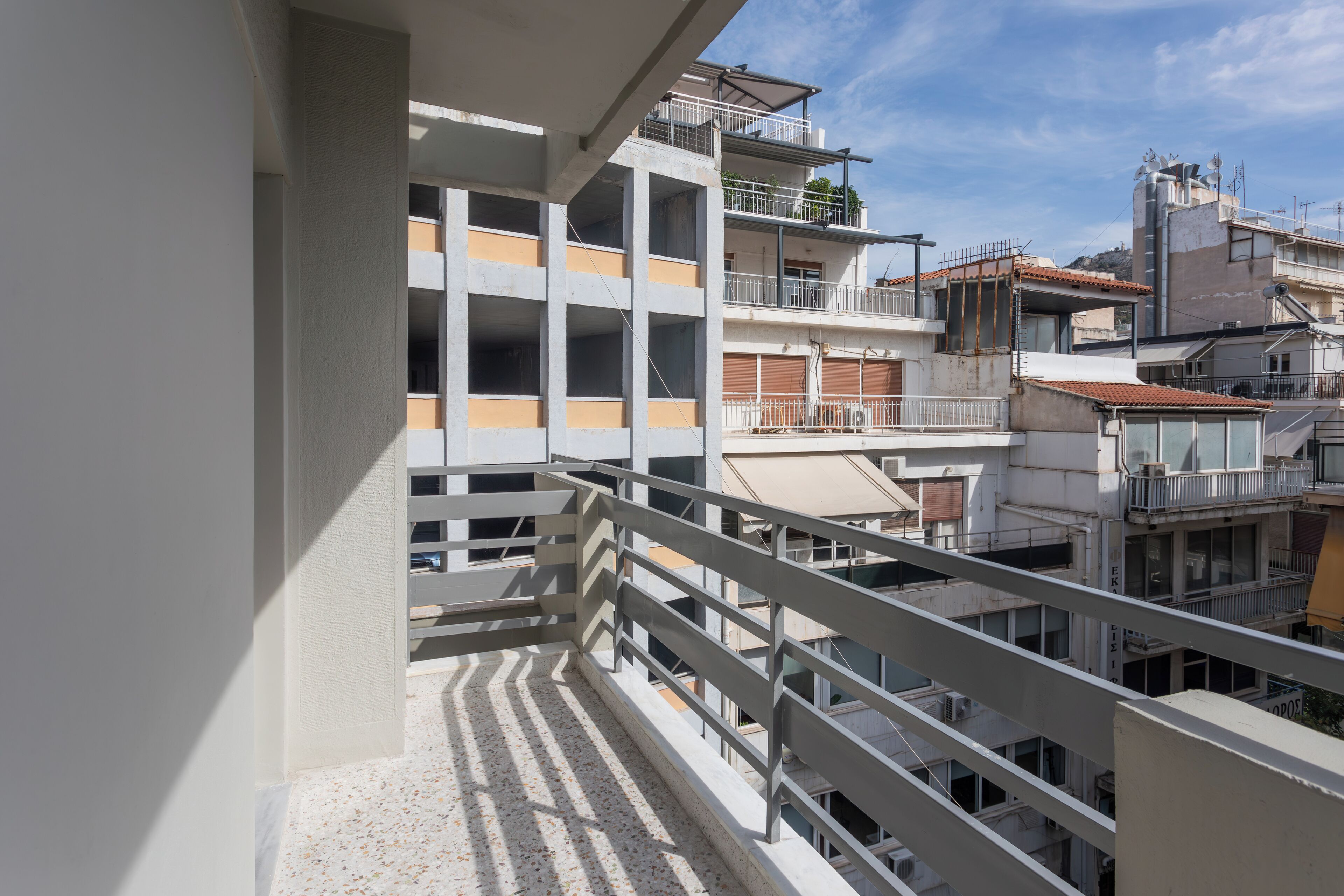 A multi-story residential building with balconies, railings, and a clear sky.