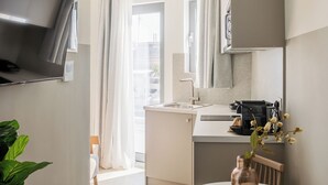 A modern kitchen with a built-in TV, a dining area with a table and chairs, and a large window with curtains. - SOL by Zoia Living (Athens)
