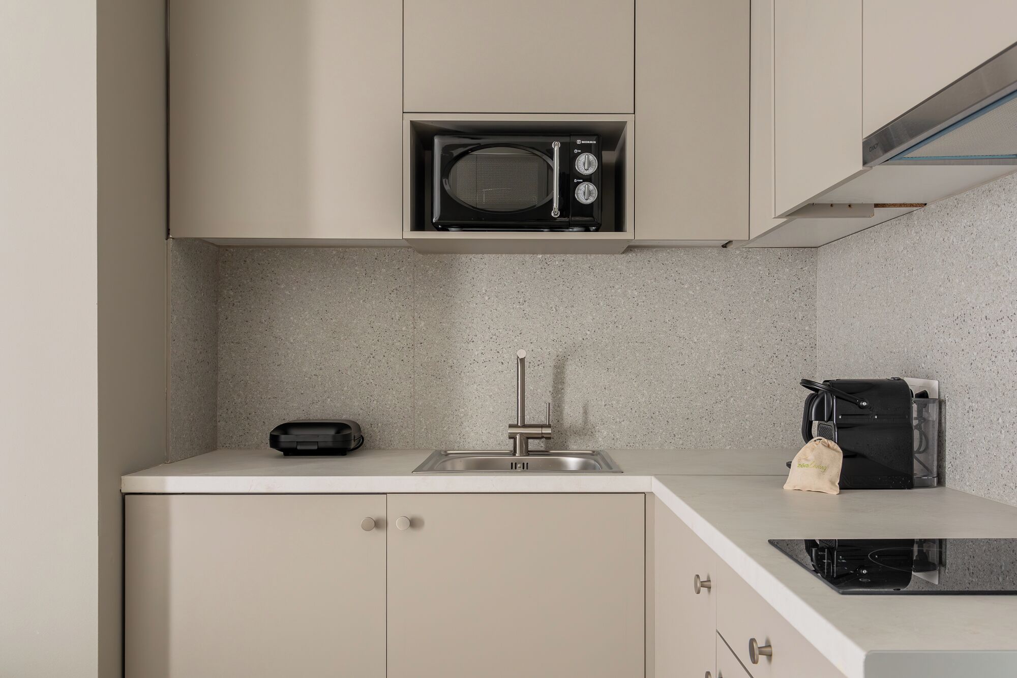 Une cuisine moderne équipée d’un four à micro-ondes encastré, d’un évier et d’une cuisinière compacte.