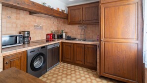 Cocina compacta con armarios de madera, lavadora, microondas y cafetera.