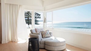 Un salon moderne avec vue sur la mer, une grande fenêtre et un coin salon confortable.