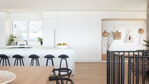 Une cuisine moderne avec un îlot central, des tabourets de bar et une table à manger.
