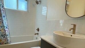 A bathroom with a bathtub, toilet, and sink. - Mount Pleasant Garden Apartment (Vancouver)