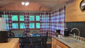 A cozy kitchen with wooden cabinets, a dining table with chairs, a refrigerator, and a sink.
