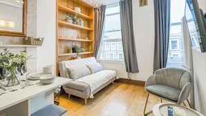 A modern room with a bed, a sofa, a dining table, and a TV. - Imperial Earls Court Apartments (London)