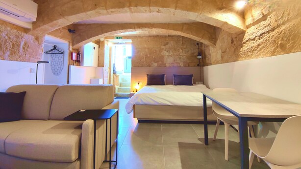 Una habitación acogedora con pared de piedra, una cama, un sofá y una mesa.