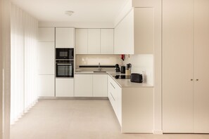 A modern kitchen with white cabinetry, a black oven, and a stainless steel sink.