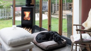 A cozy room with a glass ceiling, a wood-burning stove, a dog bed, and a chair. - Pretty Riverside Cottage, Petworth
Two Bedrooms, Sleeps 3. Dogs Welcome (Petworth)