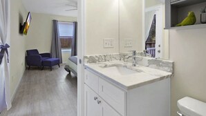 A modern bathroom with a marble sink, a toilet, and a mirror. There is a small shelf with a green plant. - Charming 3BR in St. Augustine - Walk to Downtown, Near Beach, Wifi & A/C! (St. Augustine)