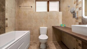 Une salle de bain équipée d’une baignoire, de toilettes et d’un meuble-lavabo avec un miroir.