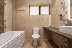 A bathroom with a bathtub, toilet, and a vanity with a mirror. - The Balkan Jewel Resort, Trademark Collection By W (Razlog)