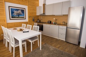 Une cuisine moderne avec des meubles blancs, un réfrigérateur en acier inoxydable et une table à manger avec des chaises.