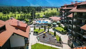 Ein Hotel mit Poolbereich, umgeben von Bergen, inklusive eines Innenhofs mit Spielplatz.