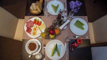 A breakfast table with plates of food, a bowl of nuts, and a basket of bread.